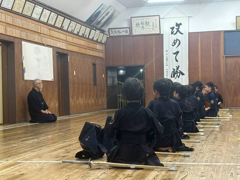 道場で正座する稽古生たちと、向かい合って見守る指導者